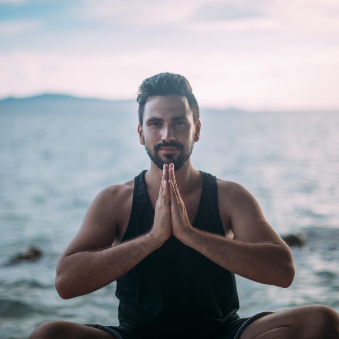 Young man doing yoga by the sea. A handsome guy is sitting on the ocean at sunset. Young man doing yoga by the sea. A handsome guy is sitting on the ocean at sunset.