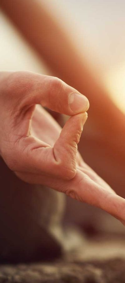 Shot focused on hands of a man doing yoga exercise on the shore Shot focused on hands of a man doing yoga exercise on the shore