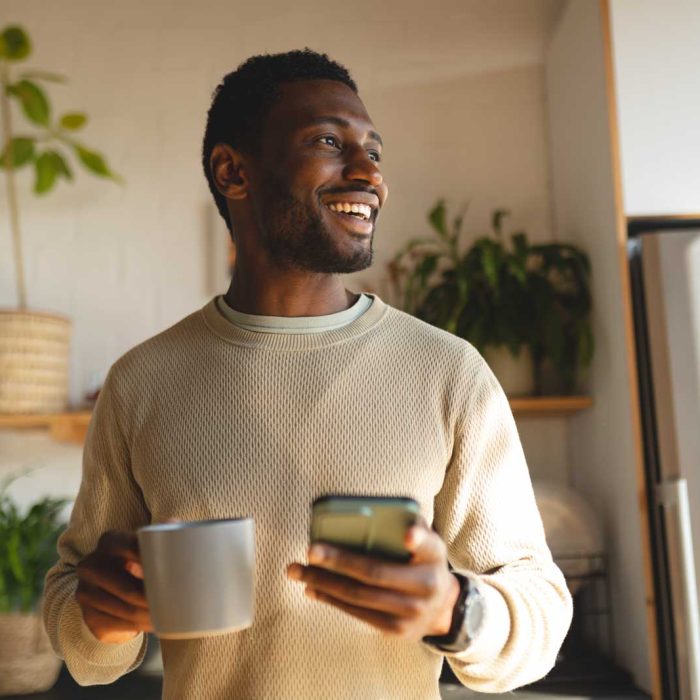 Happy african american man using smartphone and drinking coffee Happy african american man using smartphone and drinking coffee